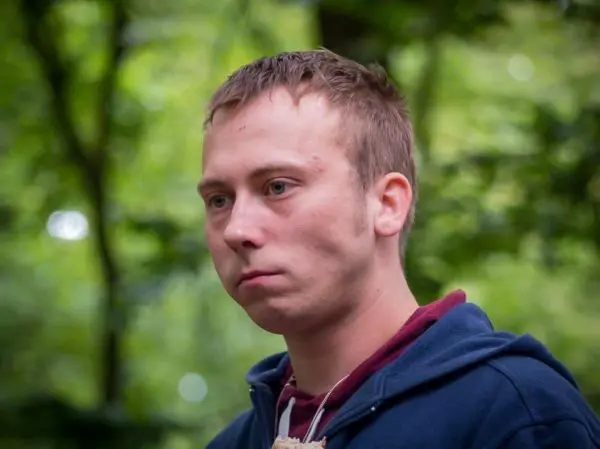 Person mit neutralem Gesichtsausdruck in einem Waldgebiet