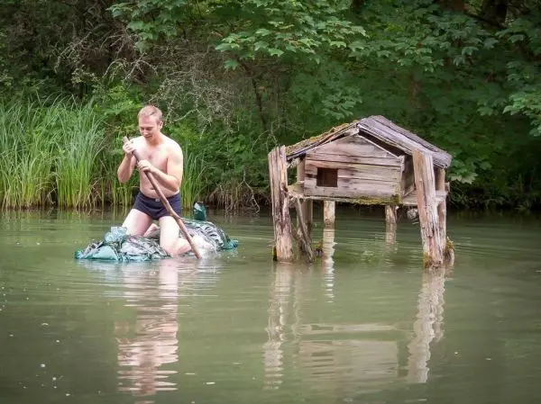 Person paddelt auf einem improvisierten Floß im Wasser