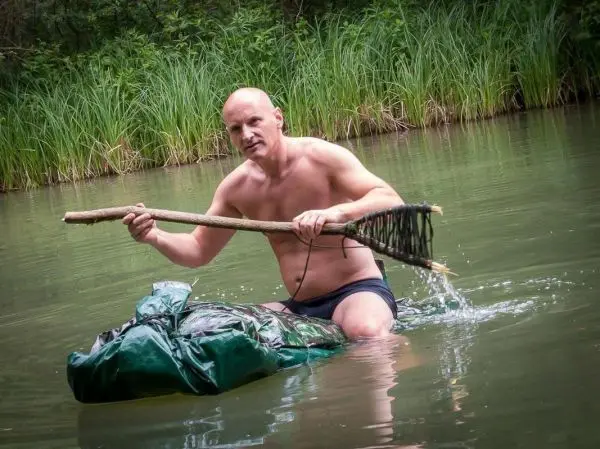 Person paddelt auf einer selbstgebauten Schwimmhilfe im Wasser