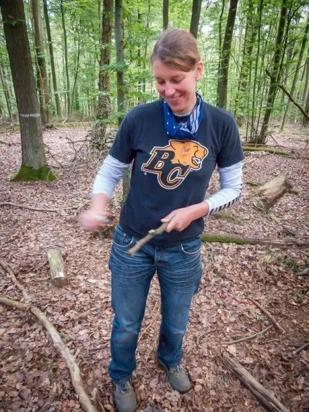 Person schnitzt mit einem Messer in einem Wald