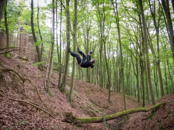 Person schwingt an einem Seil zwischen Bäumen im Wald