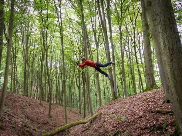 Person springt über eine Schlucht im Wald