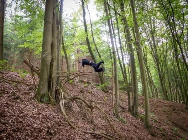 Person springt von einem Baumstamm im Wald