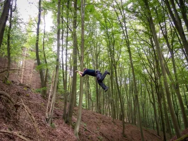 Person springt zwischen Bäumen im Wald