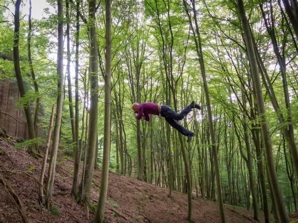 Person springt zwischen Bäumen im Wald