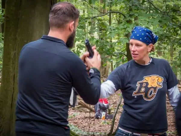 Person zeigt auf andere Person mit einer Pistole im Wald