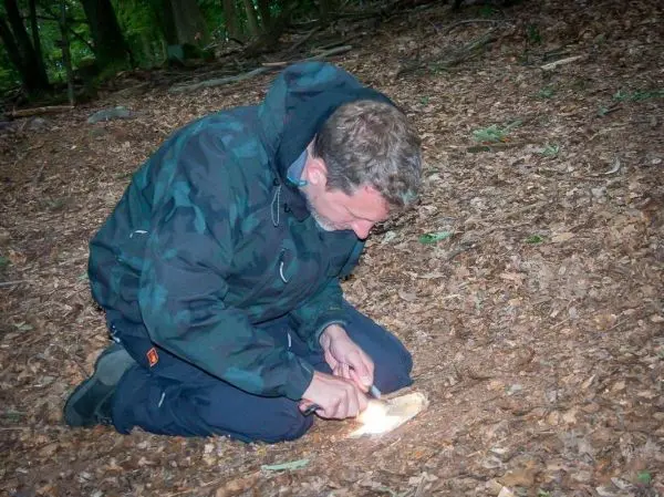 Person zündet mit einem Feuerstein Holzstück an