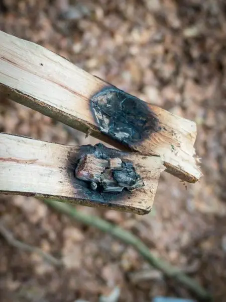 Schlagfalle (Figure-Four) mit verkohltem Zunder auf Holzstücken