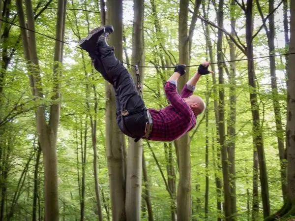 Seilquerung an einem gespannten Seil zwischen Bäumen im Wald