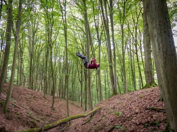 Selbstgebaute Seilquerung über einen Waldgraben mit einer Person in der Luft
