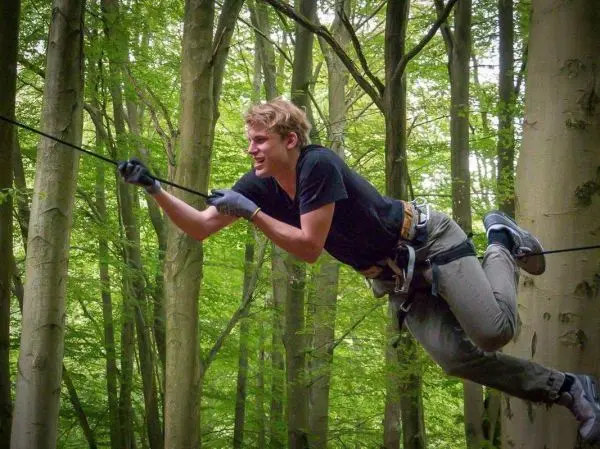 Selbstgebaute Seilquerung wird von einer Person im Wald überquert