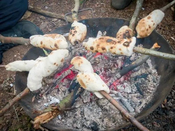 Teigstücke rösten über einem offenen Feuer in einer Feuerschale