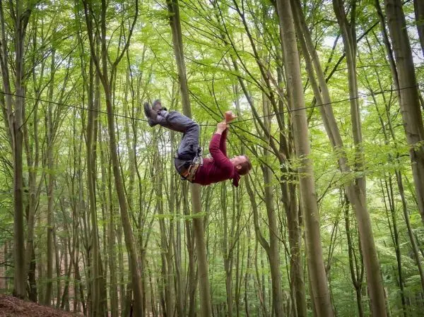 Überquert eine selbstgebaute Seilbrücke zwischen Bäumen
