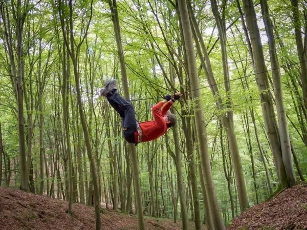 Überquert eine selbstgebaute Seilbrücke zwischen Bäumen