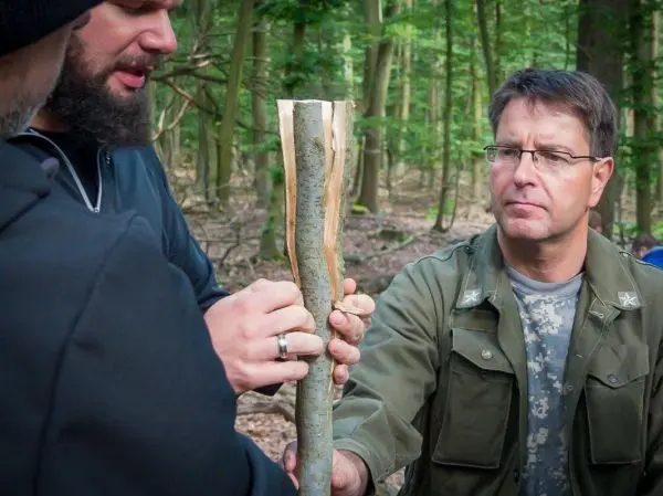 Zwei Personen halten einen gespaltenen Stock im Wald