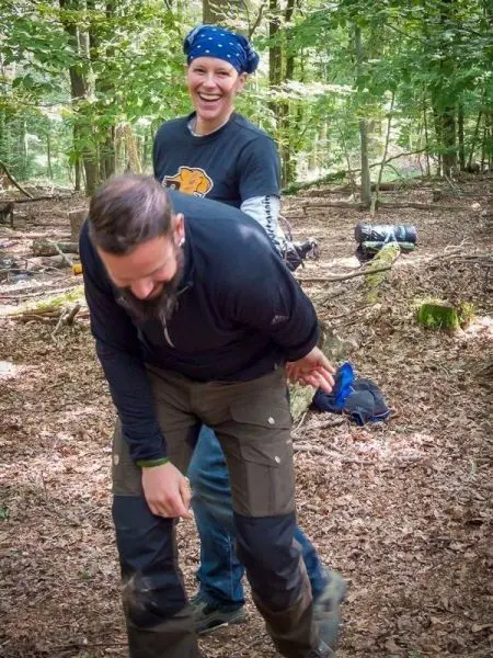 Zwei Personen in Waldumgebung, eine Person hält die andere von hinten fest