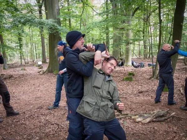 Zwei Personen üben eine Selbstverteidigungstechnik im Wald