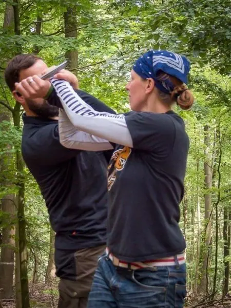 Zwei Personen üben eine Selbstverteidigungstechnik im Wald
