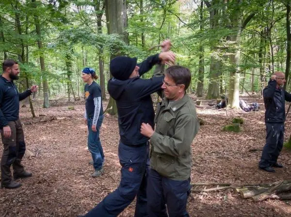 Zwei Personen üben eine Selbstverteidigungstechnik im Wald