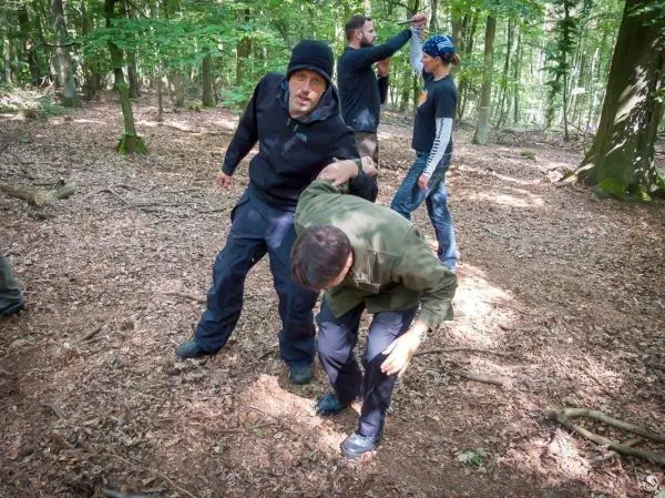 Zwei Personen üben eine Technik zur Unterstützung in einem Waldgebiet