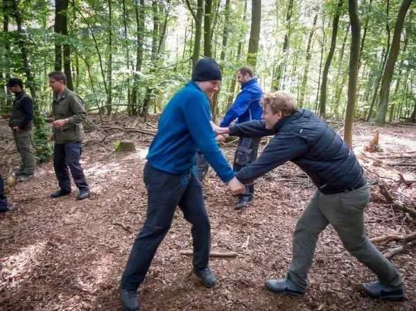Zwei Personen ziehen an einem Seil in einem Waldgebiet