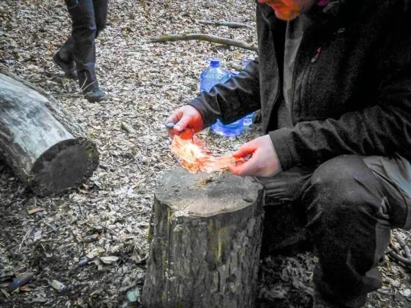 Feuerstahl erzeugt Funken auf Zunder auf einem Baumstumpf
