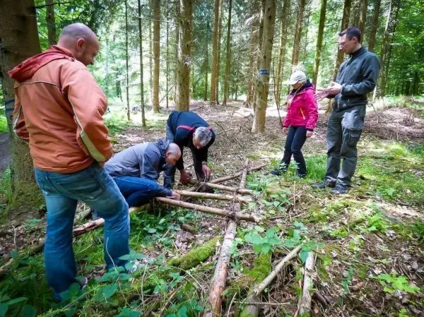 Gruppe arbeitet an einer selbstgebauten Seilbrücke im Wald beim Survival Training