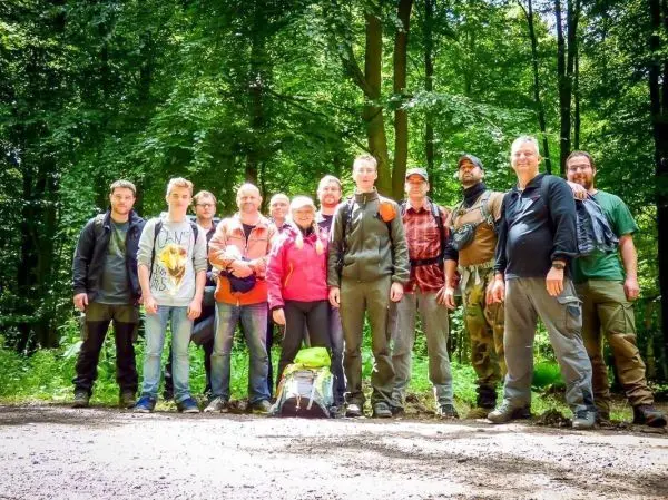 Gruppe von Personen steht auf einem Waldweg umgeben von Bäumen