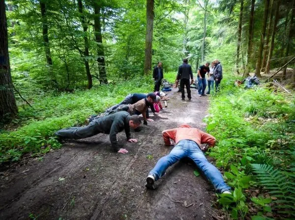 Gruppenteilnehmer führen Liegestütze auf einem Waldweg durch
