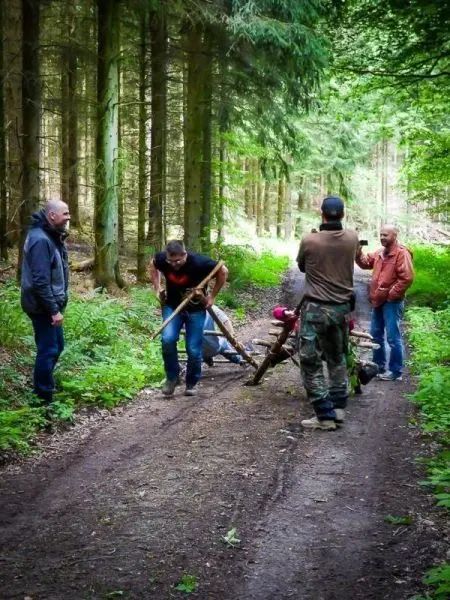 Männer arbeiten an einer selbstgebauten Konstruktion auf einem Waldweg