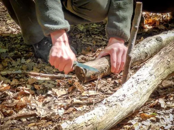 Messer schneidet in einen Holzstock auf dem Boden