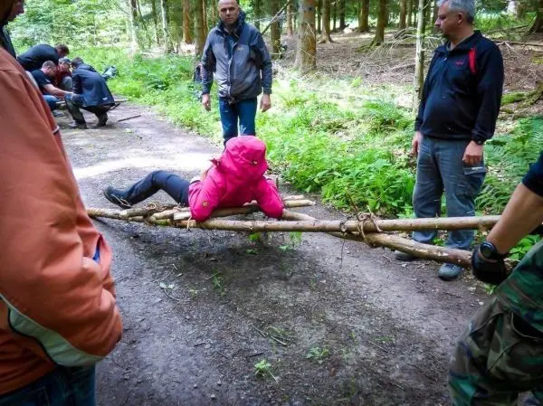 Teilnehmer überquert selbstgebaute Seilbrücke aus Ästen im Wald