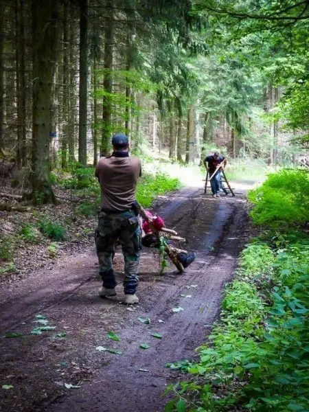 Zwei Personen arbeiten an einer improvisierten Trage auf einem Waldweg