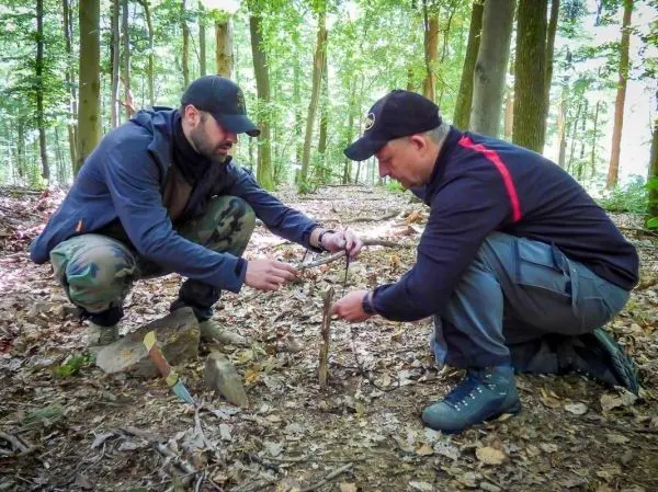 Zwei Personen bauen eine Konstruktion aus Ästen im Wald