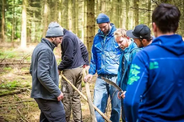 Gruppe arbeitet gemeinsam an einer Holzstruktur im Wald