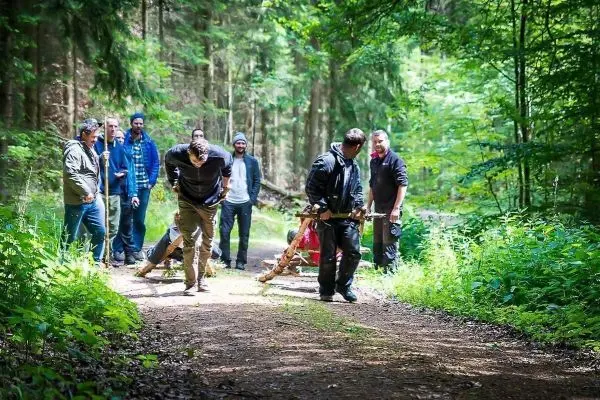 Gruppierung von Personen beobachtet selbstgebaute Trage auf Waldweg