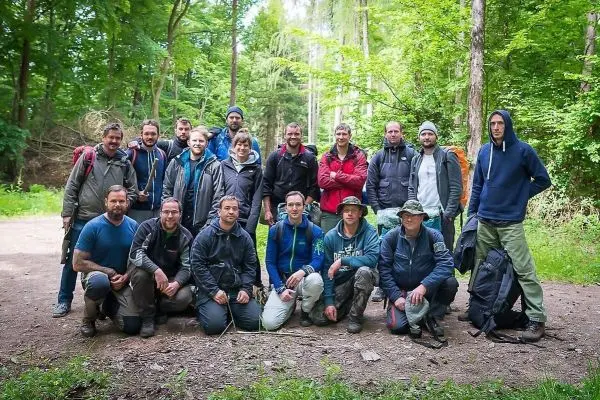 Gruppierung von Personen im Wald, ausgestattet mit Rucksäcken und Outdoor-Bekleidung