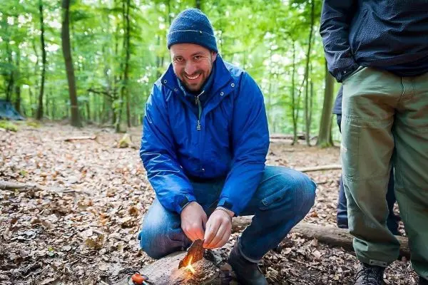 Mann entzündet Zunder mit Feuerstahl im Wald