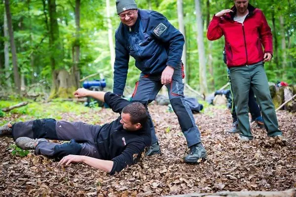 Mann liegt auf dem Boden, während ein anderer ihn unterstützt und zwei weitere Personen beobachten