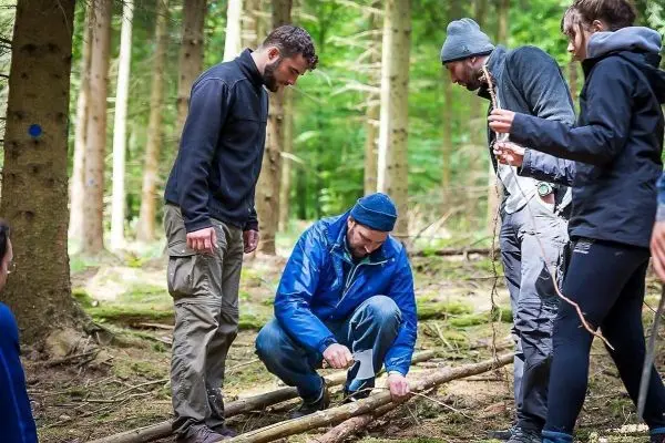 Mann schneidet mit einem Messer einen Stock im Wald