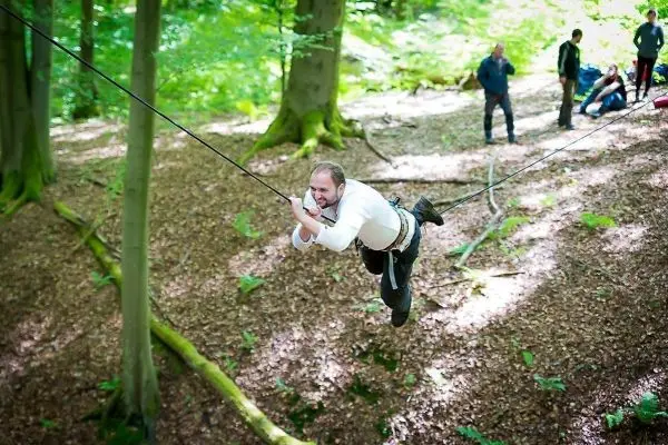 Mann überquert selbstgebaute Seilbrücke zwischen Bäumen im Wald