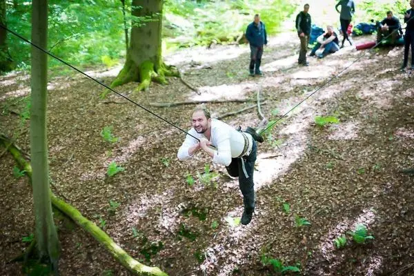 Mann überquert selbstgebaute Seilbrücke zwischen Bäumen im Wald