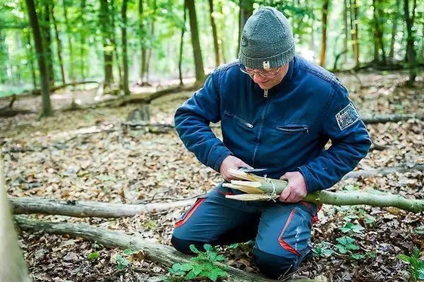 Messer bearbeitet Holzstück zur Herstellung einer Konstruktion im Wald