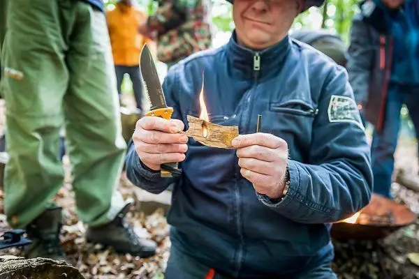 Messer hält Zunder mit kleiner Flamme in der Hand