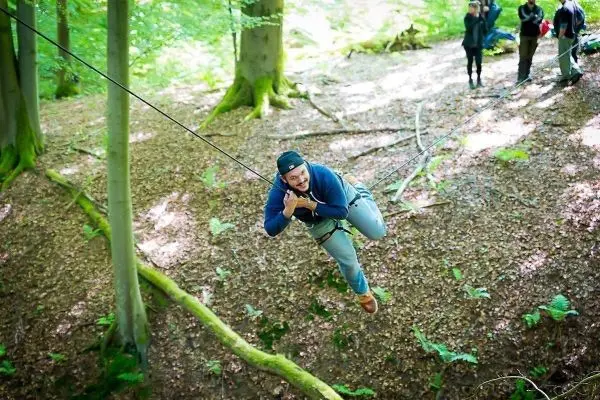 Person schwingt an einem Seil zwischen Bäumen beim Überlebenstraining