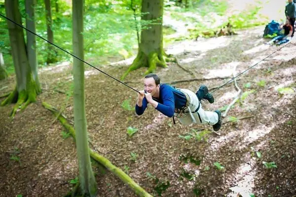 Person schwingt an Seil zwischen Bäumen