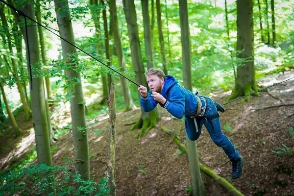 Person schwingt an Seil zwischen Bäumen