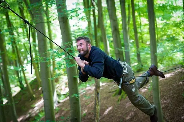 Person schwingt an Seil zwischen Bäumen