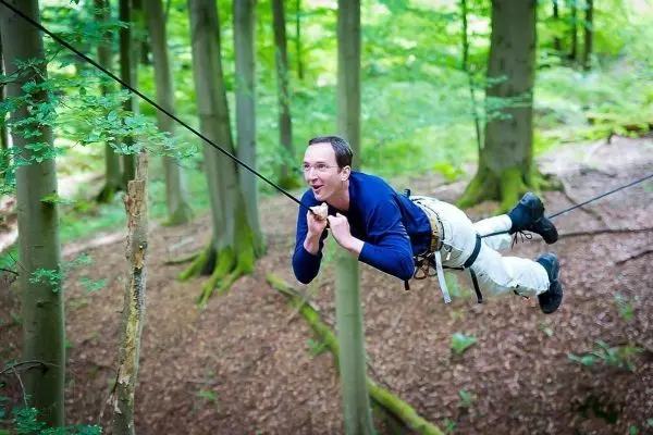 Person schwingt an Seil zwischen Bäumen im Wald