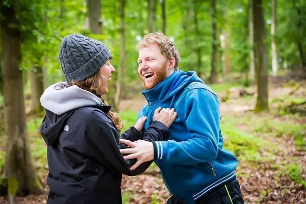 Personen lachen und halten sich in einem Wald umarmt